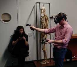 A man in VR in front of a model of the human skeleton.